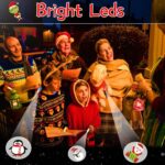 A hand wearing multiple colorful LED Christmas finger lights projecting festive images like Santa and snowmen in the dark.